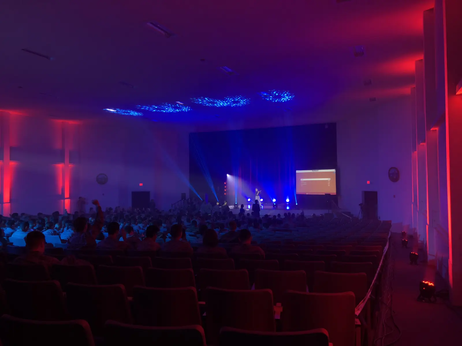 Audience viewing a red and blue illuminated stage