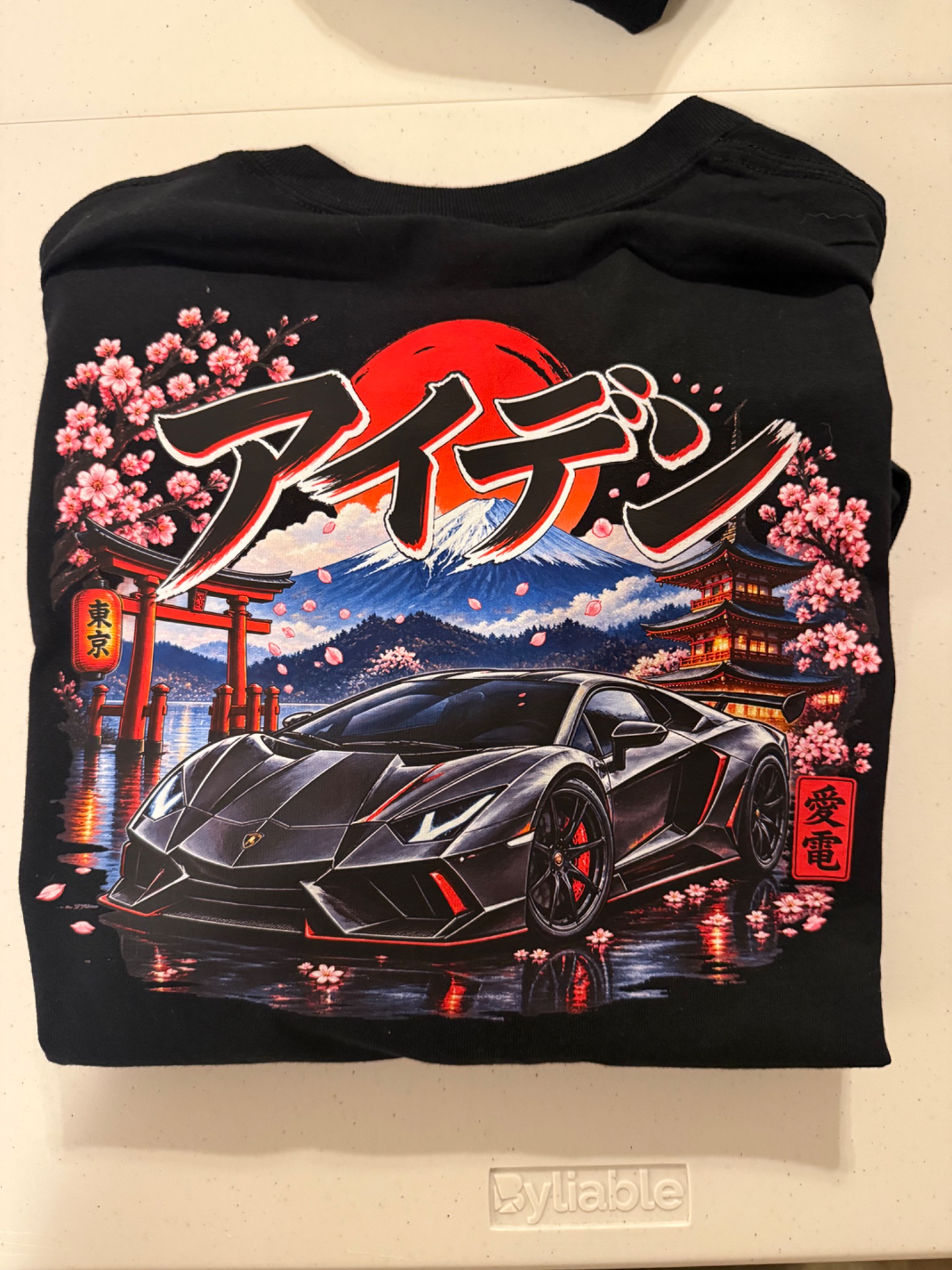Black shirt with a sports car, Japanese lettering, and cherry blossoms